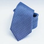Close-up of a blue patterned necktie on a white background, perfect for fashion and business themes.