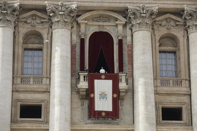Pope standing on St. Peter's Basilica balcony.